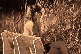 young woman sitting on the bench and reading book