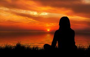 woman in meditation pose at sunset