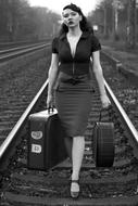 woman with suitcases on rails as a retro picture