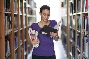 girl with books in the library near the shelves