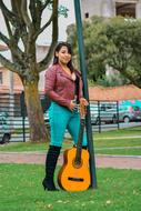 sexy Woman in Leather Jacket posing with guitar outdoor