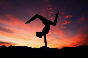 silhouette of a girl in a yoga pose on the background of a red sunset