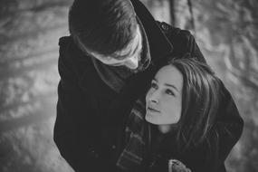 black and white photo of a couple in love on the street in winter