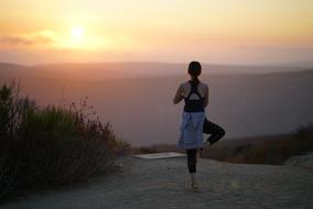 girl in yoga pose at dusk in the mountains