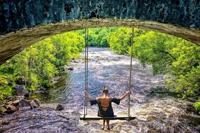 girl riding a swing over the river