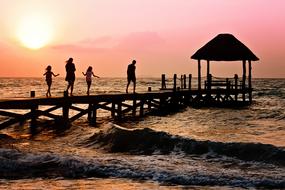 Family with two Children on pier above sea at sunrise