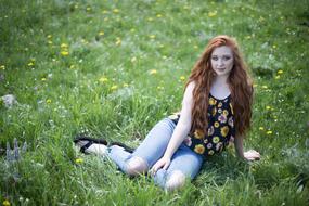 long haired young girl sits on Grass at Summer