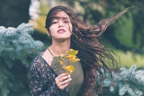 Portrait of the beautiful girl with waving hair, with the beautiful, yellow and green flowers, among the colorful plants