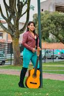 photo of a girl in a leather jacket with a guitar near a street lamp