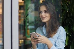 photo through the glass of a smiling girl with a smartphone