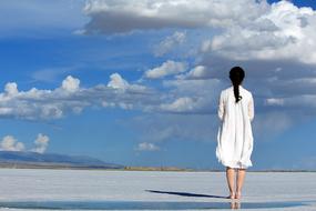 girl in a white dress against the sky with clouds