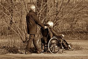 black and white photo man rolls his wife in a wheelchair