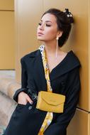 stylish girl with yellow handbag near the wall