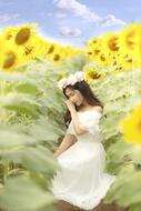 Girl in white dress among sunflowers