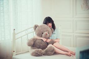 Asian girl with a teddy bear on the bed