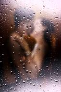 lovers kiss through wet glass