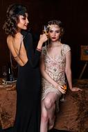 photo of girls with glasses of champagne in vintage dresses with vintage hairstyles