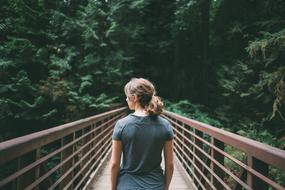 Girl Walking away on bridge at forest