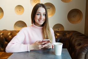 girl with a smartphone and a glass of coffee in a cafe