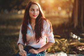 Portrait of the smiling girl in white shirt, among the colorful plants in sunlight