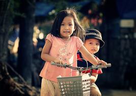 Cute children, riding on the bike, together