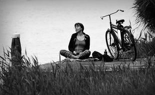 black and white photo of a girl resting on a wooden pier