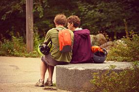 couple of tourists is sitting on a stone in a park