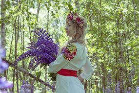 girl in a colorful russian folklore costume with a purple bouquet of flowers