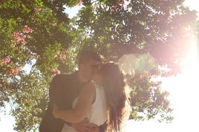 couple in love kisses in the sun on a background of trees