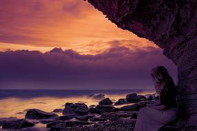 Thinking girl sits on Beach at scenic Sunset