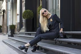 Fashion Model, sexy girl in black clothing sits on stairs outdoor