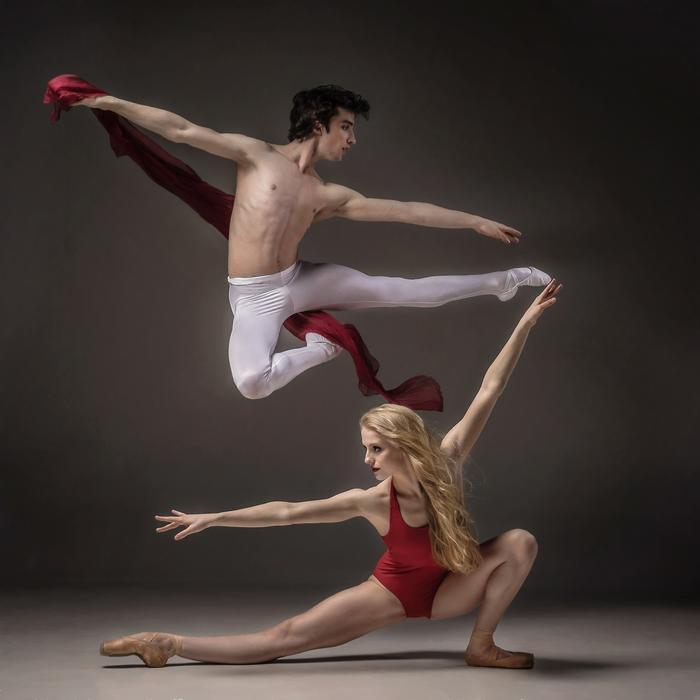 Couple in red and white clothing, dancing at gray background