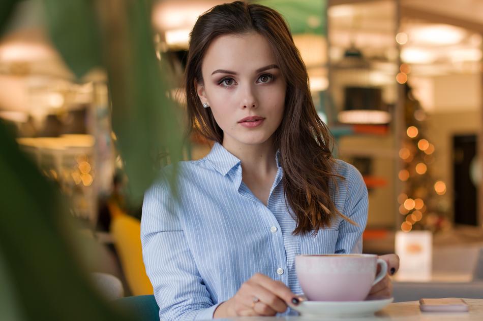 Portrait of the woman with make-up and in blue shirt, drinking coffee