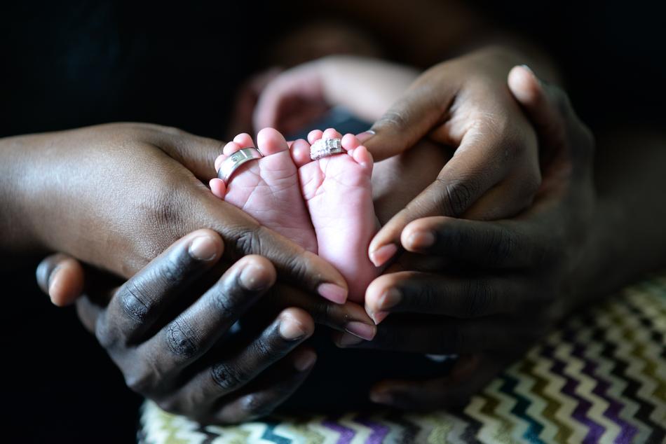 Babyâs feet with Wedding Rings on hands of young couple
