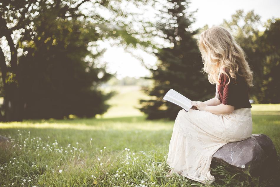 blonde with a book in the garden in a blurred background