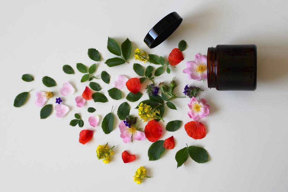 flower petals and leaves and an open jar