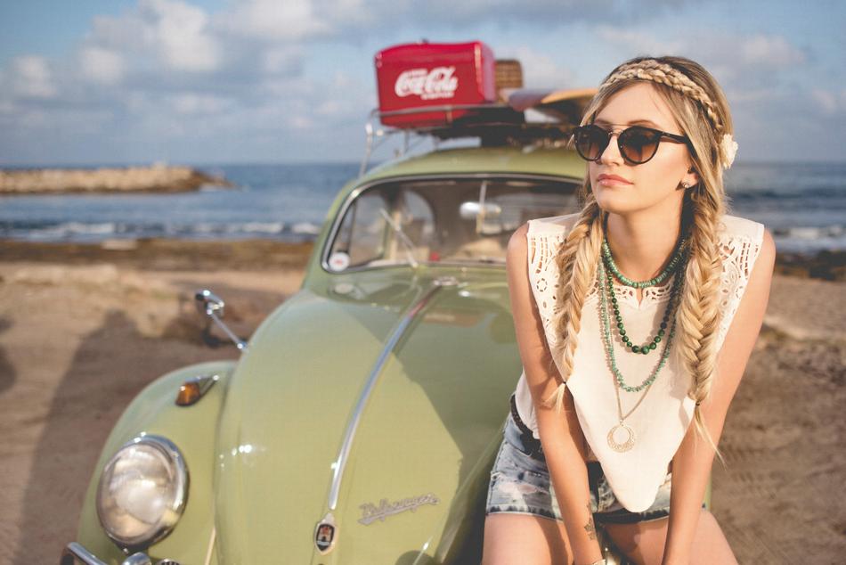 Beautiful blonde girl with the retro Beetle car on the beach
