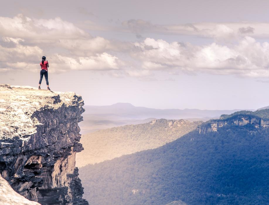 Woman on the edge of the cliff on the landscape