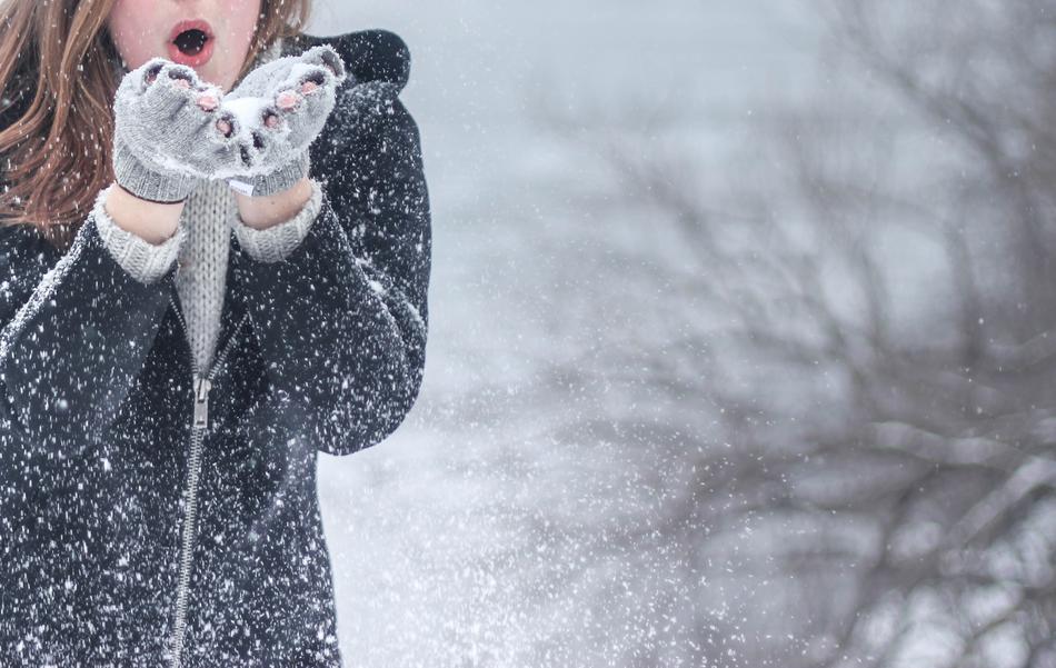photo of a girl blowing on the snow