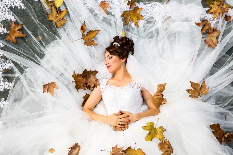 Bride, in the beautiful, white wedding dress, in the colorful and beautiful autumn leaves