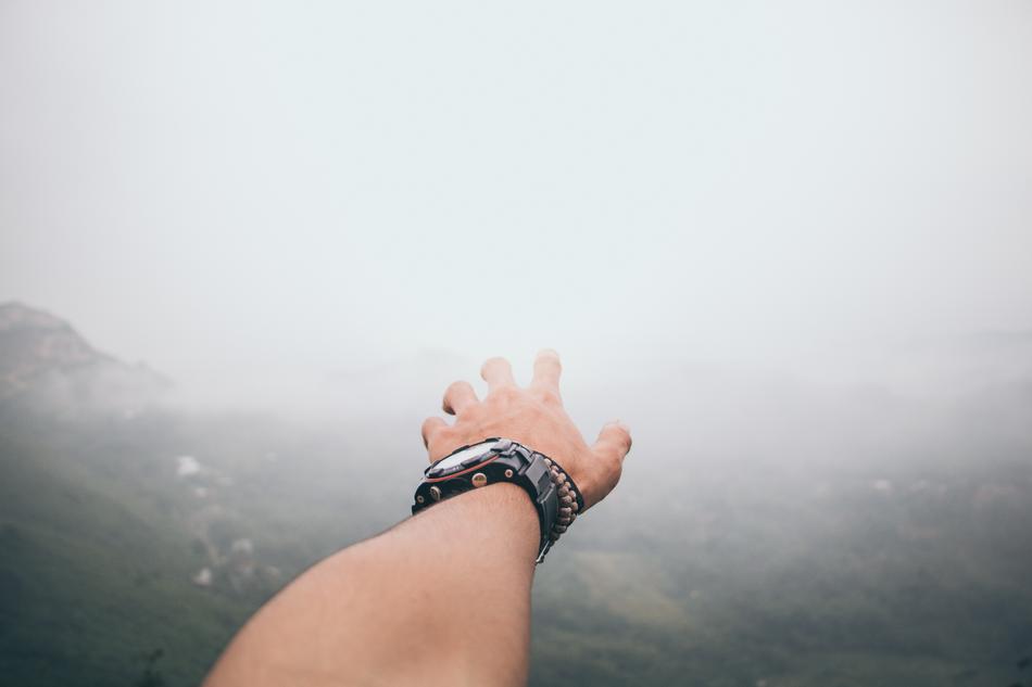 Adult, showing hand with the watch, on the beautiful, foggy landscape with the mountains