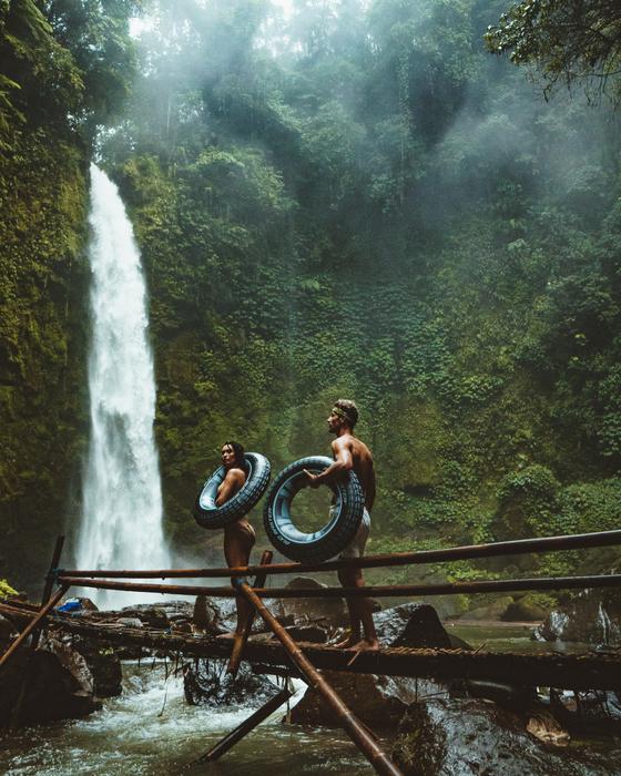 photo of a couple with rubber rings on the background of a waterfall