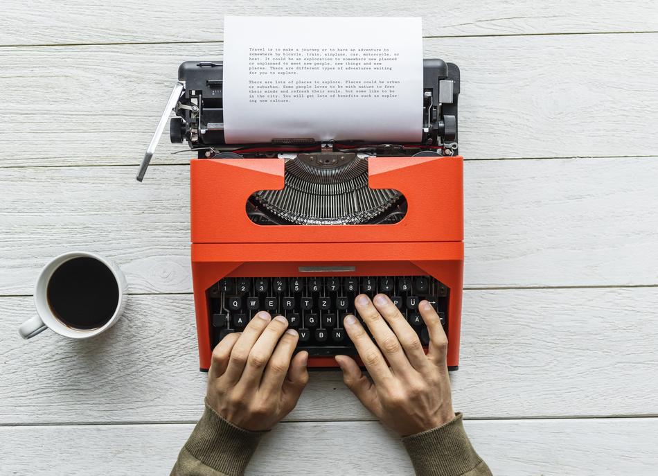 journalist works on a red retro typewriter