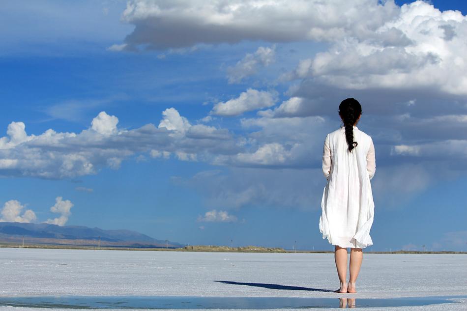 girl in a white dress against the sky with clouds