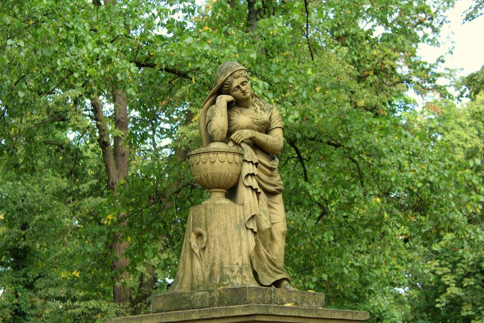 Beautiful figurine of the woman, among the beautiful, green trees