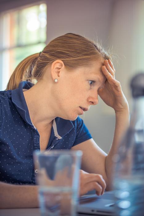 Adult Annoyed woman holding her head at table