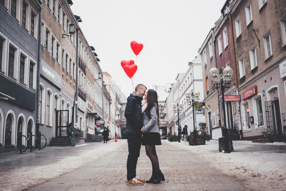 Couple with the red heart balloons, kissing on the beautiful street