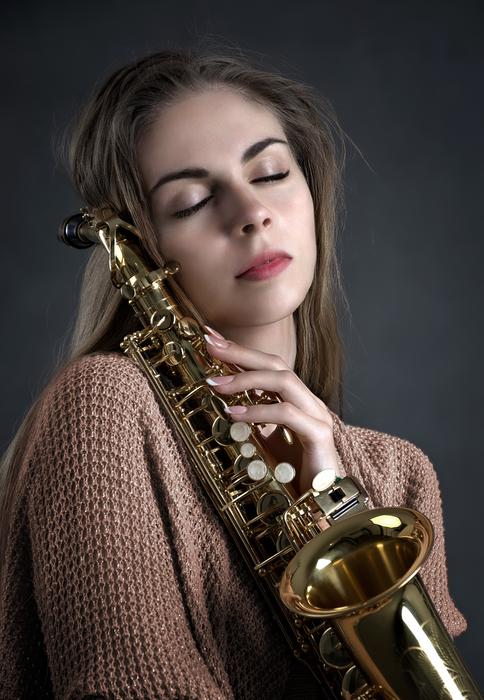 Portrait of the beautiful, posing girl with the shiny saxophone
