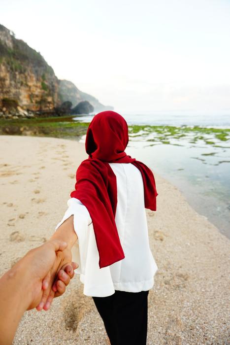 Couple with Muslim woman in red hijab, on the beautiful sandy beach