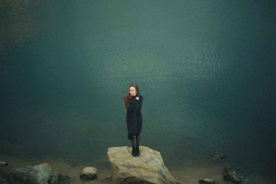 sad woman on stone near water
